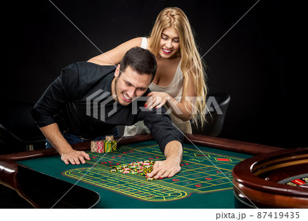 Young couple celebrating win at roulette table in casino. 87419435