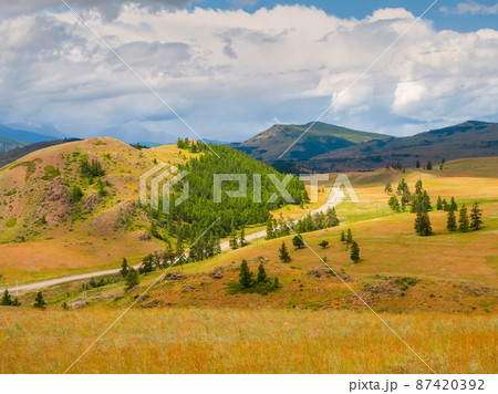 Picturesque summer mountain landscape with road through the pass. Turn on the asphalt mountain highway. Chuysky tract and a view of the North Chuysky Mountain range in the Altai, Siberia, Russia. 87420392