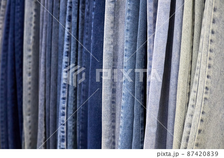Various blue Jeans on a hanging rack in the clothes store. Close-up, selective focus Various blue Jeans on a hanging rack in the clothes store. Close-up, selective focus 87420839