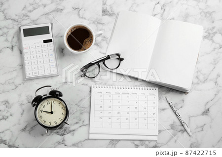 Flat lay composition with calendar and cup of coffee on white marble table 87422715