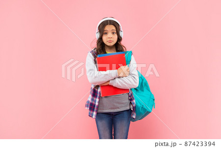 sad child listen music in headphones carry backpack with workbook on pink background, ebook sad child listen music in headphones carry backpack with workbook on pink background, ebook 87423394