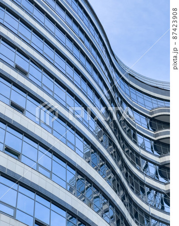Curved lines of the facade of a large building, reflection of the blue sky in the glass walls, conceptual design Curved lines of the facade of a large building, reflection of the blue sky in the glass walls, conceptual design 87423908