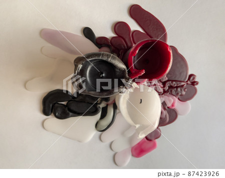 top view of several molten candles of different colors, background white, wax spread in different directions, black, white and burgundy color top view of several molten candles of different colors, background white, wax spread in different directions, black, white and burgundy color 87423926