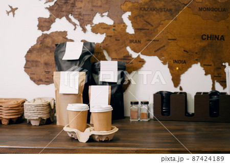 Disposable paper cups with coffee for takeaway food. Packages with coffee on counter for self-service, drink to go. 87424189