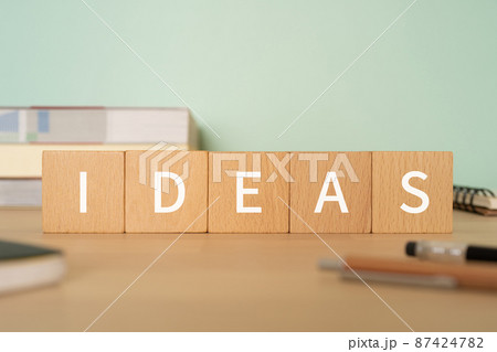 アイデアのイメージ｜「IDEAS」と書かれた積み木、参考書、ノート、ペン 87424782