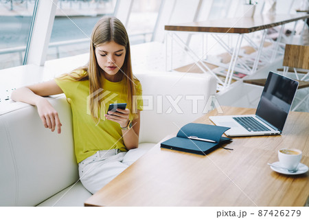 Student browsing mobile phone in cafe Student browsing mobile phone in cafe 87426279