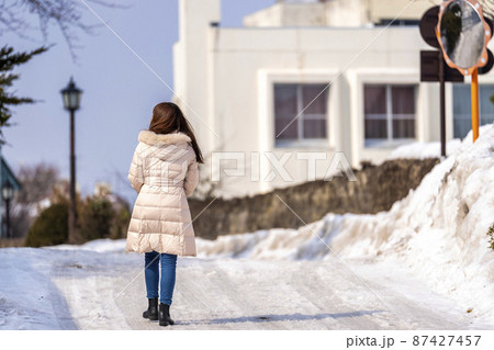 雪道を歩く女性の後ろ姿 87427457