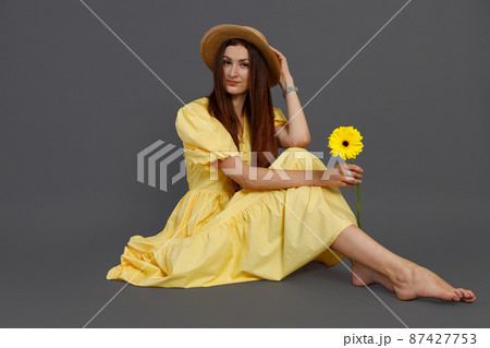 Charming woman with flower sitting on the floor in studio Charming woman with flower sitting on the floor in studio 87427753