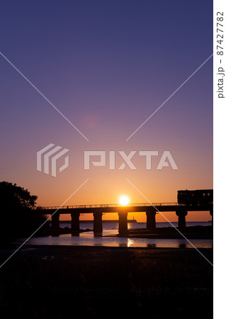 マジックアワーと共に昇る日出の宮崎県日南市山王の日南海岸山王浜を走るJR九州キハ40日南線通勤列車 87427782