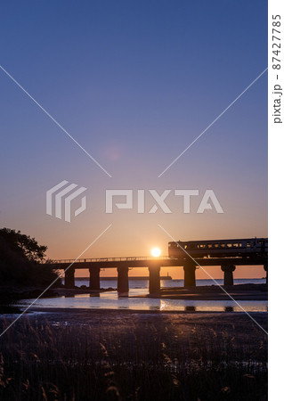 マジックアワーと共に昇る日出の宮崎県日南市山王の日南海岸山王浜を走るJR九州キハ40日南線通勤列車 87427785