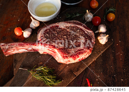 Sliced grilled thai steak served on white plate with grilled sliced lemon, tomatoes, garlic 87428645