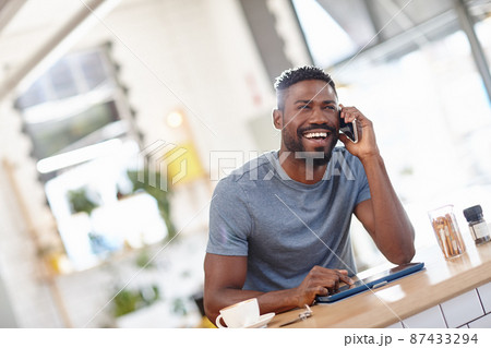 Well have the entire place to ourselves. Cropped shot of a handsome man sitting in a coffee shop using a cellphone and tablet. Well have the entire place to ourselves. Cropped shot of a handsome man sitting in a coffee shop using a cellphone and tablet. 87433294