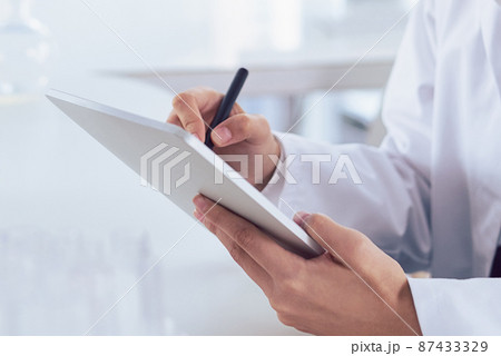 I can mark that off as done. Cropped shot of a unrecognizable scientists hands making notes on a digital tablet inside of a laboratory. 87433329