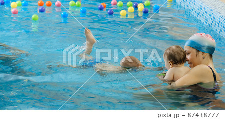 Toddler child learning to swim in indoor swimming pool with teacher. and general physical activity for kids, early development. Boy kid trained to kick legs. Group with instructor in water Toddler child learning to swim in indoor swimming pool with teacher. and general physical activity for kids, early development. Boy kid trained to kick legs. Group with instructor in water 87438777