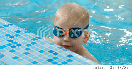 Toddler child learning to dive in indoor swimming pool with teacher. Standing on side, balancing and general physical activity for kids in water, early development. Boy kid instructed 87438787