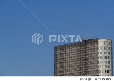 真っ青な空のもと、足場が組まれてシートが被さっている建物の風景 真っ青な空のもと、足場が組まれてシートが被さっている建物の風景 87439309