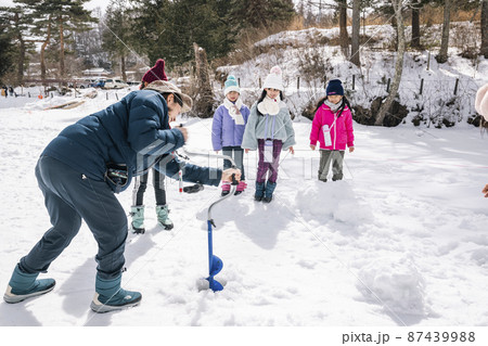 ワカサギ釣り　全面結氷した湖に穴をあける小学生 87439988
