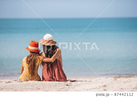 Beautiful mother and daughter at the beach enjoying summer vacation Beautiful mother and daughter at the beach enjoying summer vacation 87442112