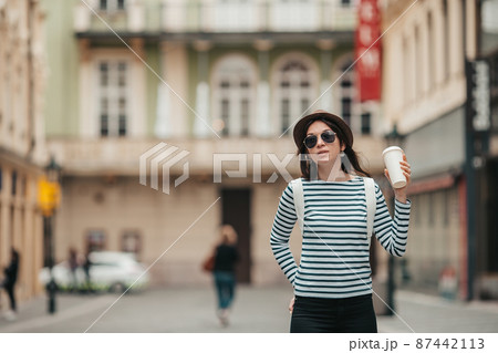 Happy young woman in hat on the street of european city. Happy young woman in hat on the street of european city. 87442113