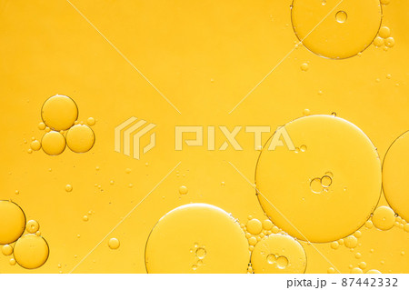 Golden yellow abstract oil bubbles or face serum background. Oil and water bubbles macro photography. 87442332