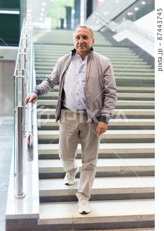 Middle aged man going down stairs in mall 87443745