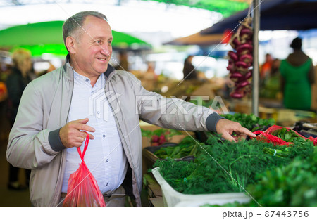 Man choosing vegetables in market Man choosing vegetables in market 87443756