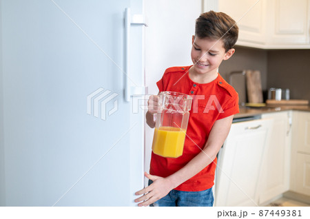 Smiling pleased boy closing the fridge door 87449381