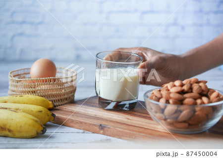 glass of milk, banana, almond nut on table  87450004