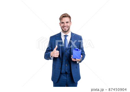 businessman in businesslike suit hold gift box as business reward showing thumb up, giftbox. 87450904