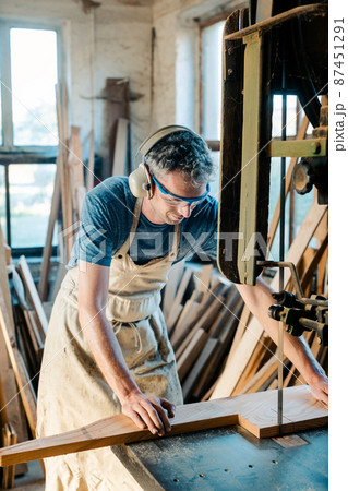 Carpenter on the band saw in his wood workshop 87451291