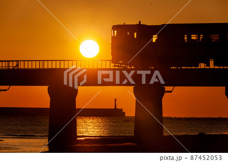 朝日で黄金色に染まった宮崎県日南市の日南海岸山王浜を走るJR九州キハ40日南線通勤列車 87452053