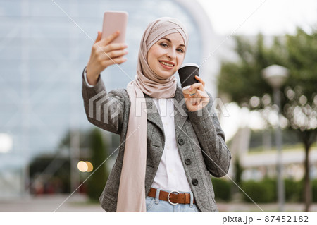 Young Muslim businesslady economist in formal wear, holding a cup of coffee Young Muslim businesslady economist in formal wear, holding a cup of coffee 87452182