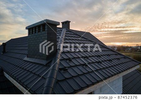 Snow guard for safety in winter on house roof top covered with ceramic shingles. Tiled covering of building 87452376