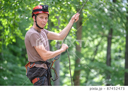 Man belays his partner climber with belaying device and rope. Climber's handsman holding equipment for rock mountaineering security. 87452473