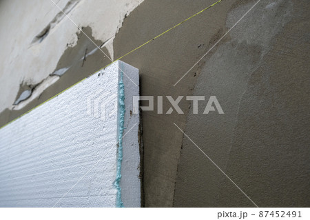 Installation of styrofoam insulation sheets on house facade wall for thermal protection. 87452491