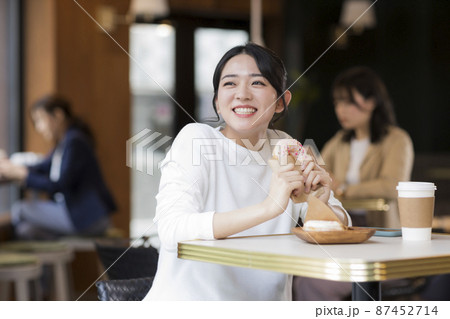 カフェでドーナツを食べる若い女性 カフェでドーナツを食べる若い女性 87452714