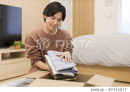 ダンボールに洋服を入れる男性  87453077