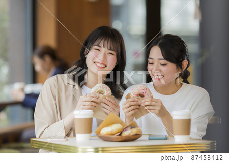カフェでドーナツを食べる若い女性 87453412