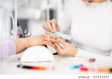 Woman hands, with which the manicure master files nails 87459345