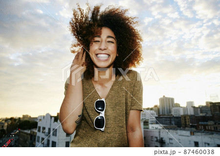 Portrait of smiling Hispanic woman on urban rooftop at sunset 87460038