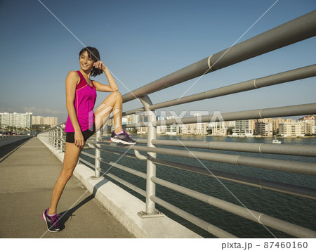 United States, Florida, Sarasota, Smiling woman stretching on bridge on sunny day 87460160