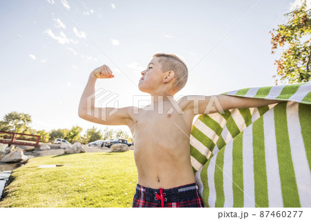Shirtless boy (8-9) flexing muscles in garden Shirtless boy (8-9) flexing muscles in garden 87460277