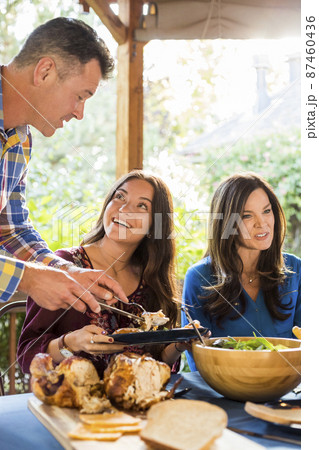 Man serving roasted turkey to smiling woman at dining table 87460436