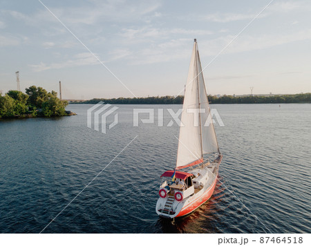 Red ship with open sails in the river with beautiful landscape 87464518