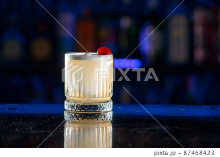 Yellow beige drink with ice and juice. raspberry topping Yellow beige drink with ice and juice. raspberry topping 87468423