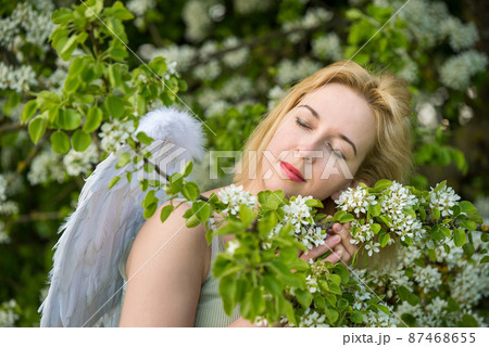 Beautiful feminime woman with white wings with white spring flowers. Beautiful feminime woman with white wings with white spring flowers. 87468655