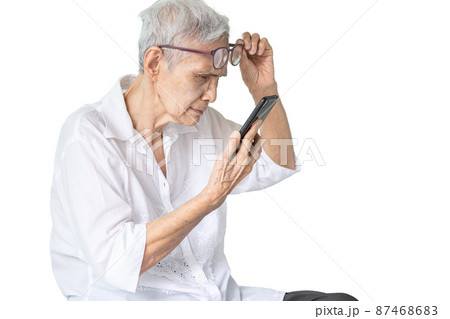 Asian senior woman with eye glasses,try to read messages,gaze at the small text on mobile phone,age related macular degeneration,blurred vision,poor eyesight problems,eye disease of the old elderly 87468683