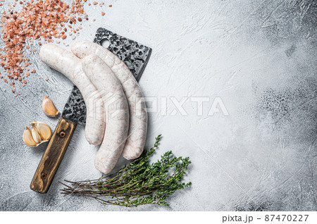 Raw Bavarian traditional white sausages on a meat cleaver. White background. Top view. Copy space Raw Bavarian traditional white sausages on a meat cleaver. White background. Top view. Copy space 87470227