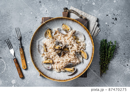 Italian Risotto with clams in a rustic plate with herbs. Gray backgroud. Top view 87470275