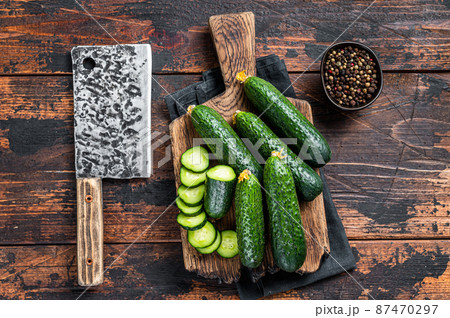 Sliced Green Cucumbers on a wooden cutting board. Dark Wooden background. Top view Sliced Green Cucumbers on a wooden cutting board. Dark Wooden background. Top view 87470297